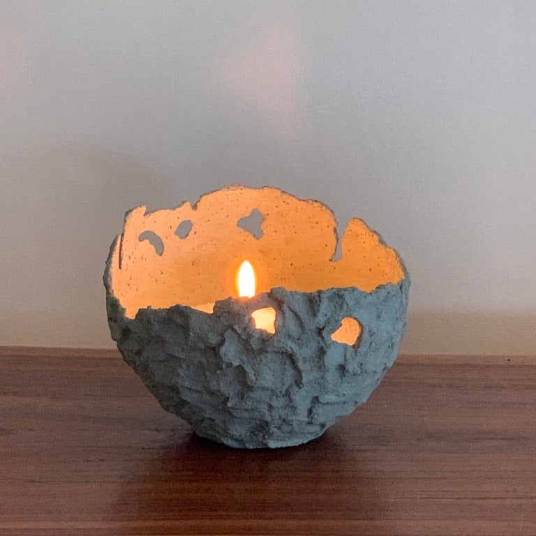 Concrete Hatchling bowl with candle sand and flame on wooden table